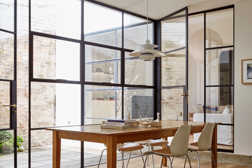 Foto di una sala da pranzo design chiusa con pareti bianche, parquet chiaro e pavimento beige