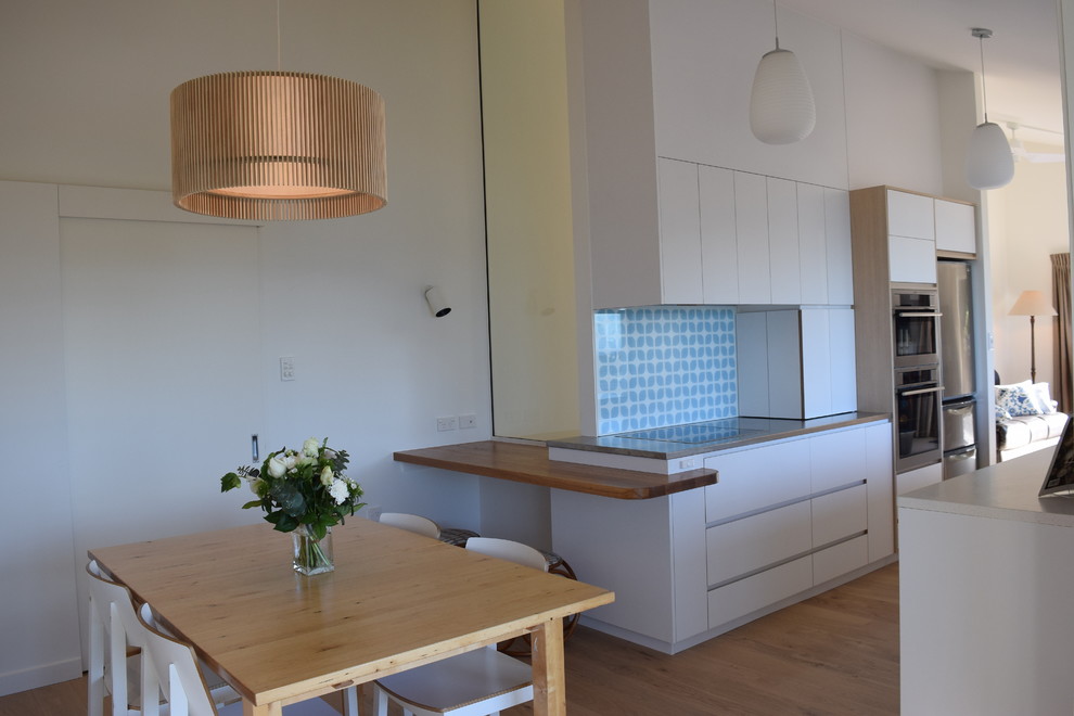 Exemple d'une salle à manger ouverte sur la cuisine scandinave de taille moyenne avec un mur blanc, un sol en bois brun et un sol marron.