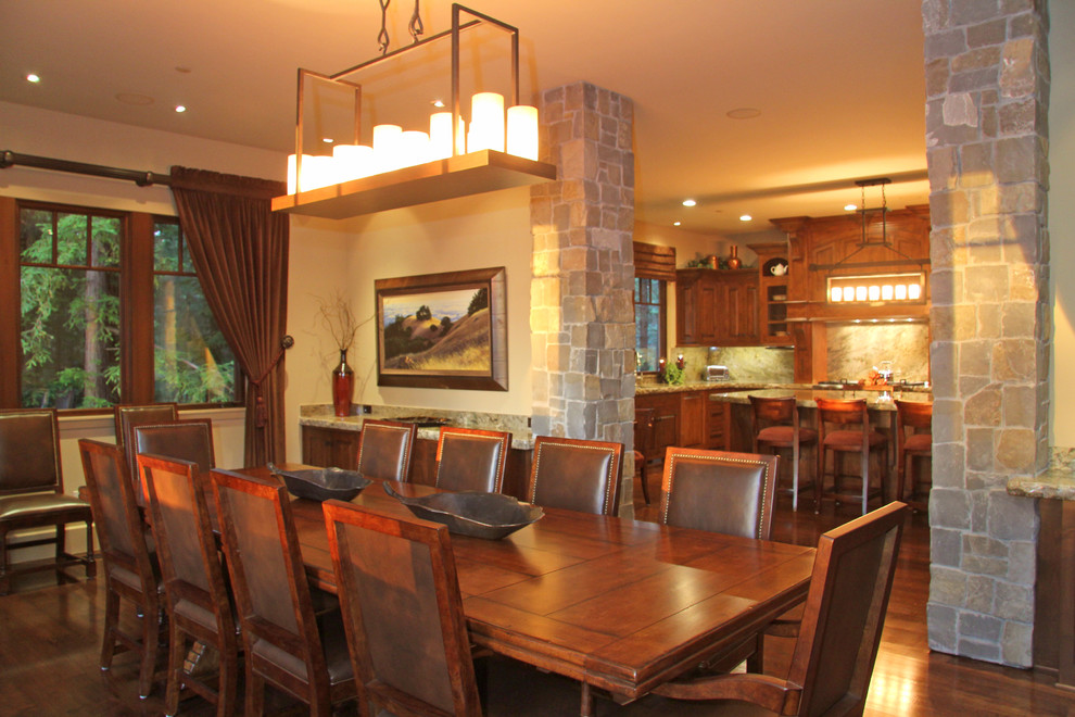 Immagine di una grande sala da pranzo aperta verso la cucina tradizionale con pareti beige, parquet scuro e nessun camino