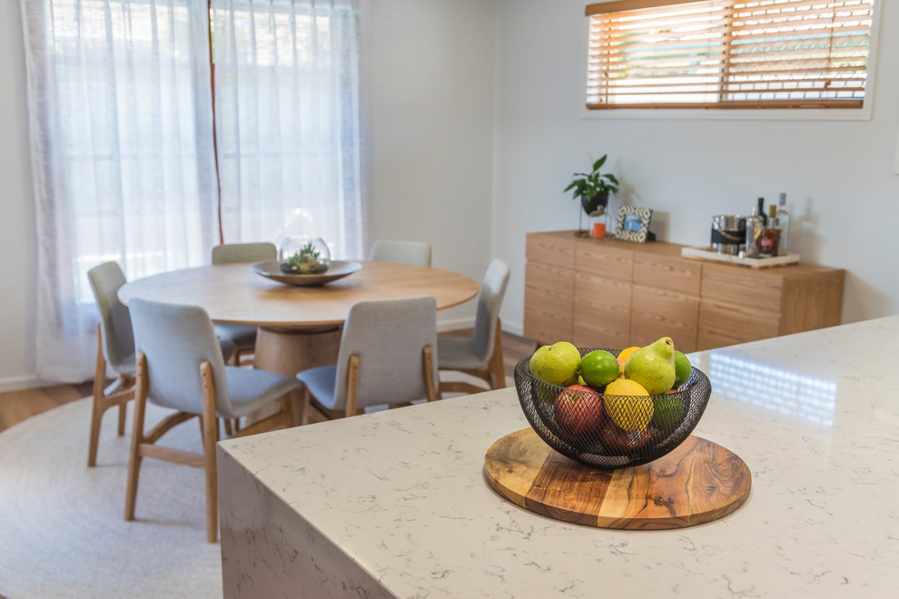 This is an example of a medium sized scandi open plan dining room in Brisbane with light hardwood flooring.