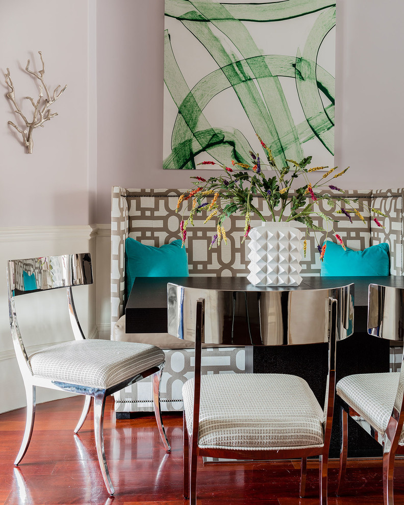 Immagine di una sala da pranzo aperta verso il soggiorno design di medie dimensioni con pareti viola, pavimento in legno massello medio, camino classico e cornice del camino in intonaco