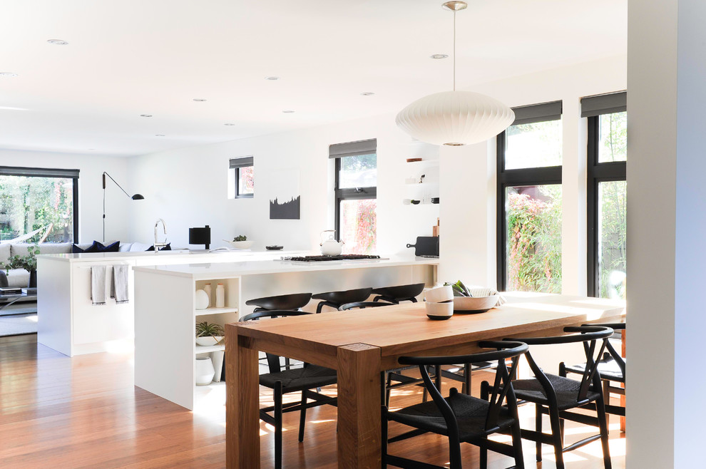 This is an example of a contemporary dining room in Vancouver with white walls, medium hardwood flooring and brown floors.