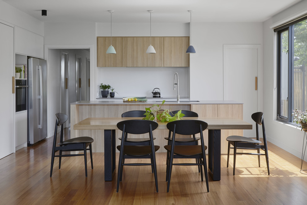 Cette photo montre une salle à manger ouverte sur la cuisine tendance avec un mur blanc, un sol en bois brun, aucune cheminée et un sol marron.
