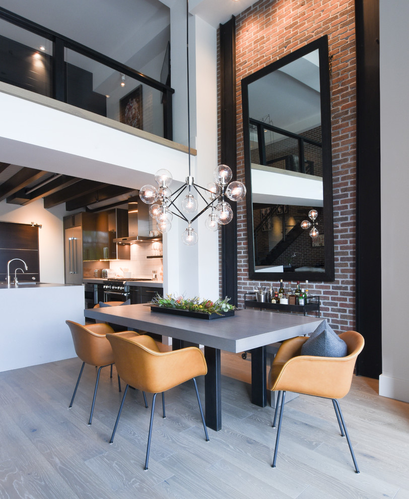 Immagine di una sala da pranzo aperta verso la cucina industriale con pareti bianche e pavimento grigio