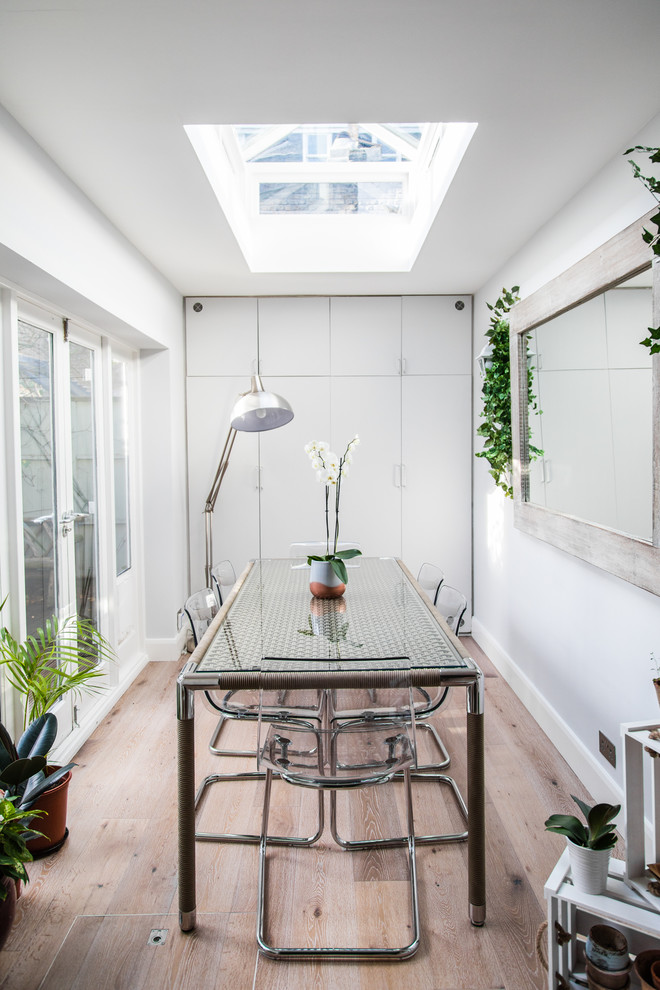 Geschlossenes Modernes Esszimmer mit weißer Wandfarbe, braunem Holzboden und braunem Boden in London