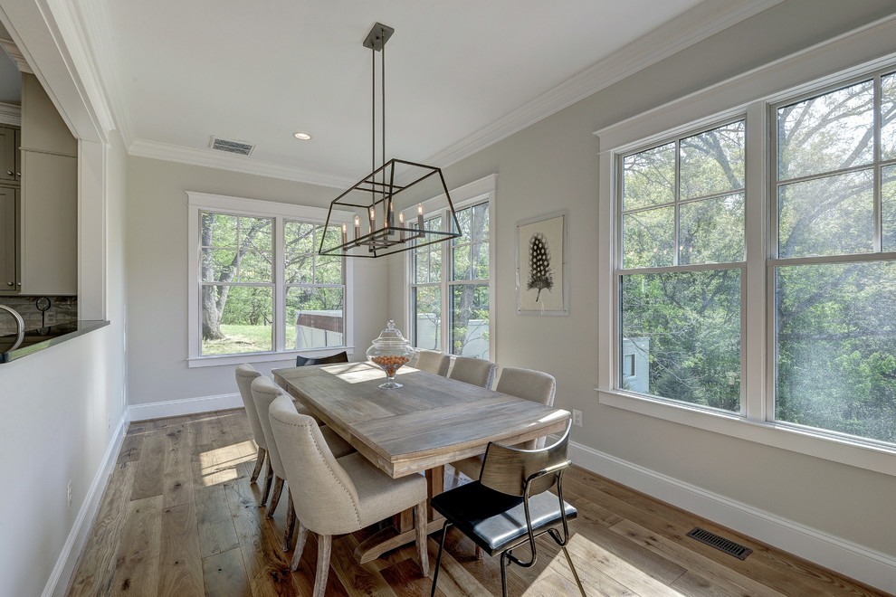 Foto di una sala da pranzo aperta verso la cucina minimalista con parquet chiaro e pareti grigie