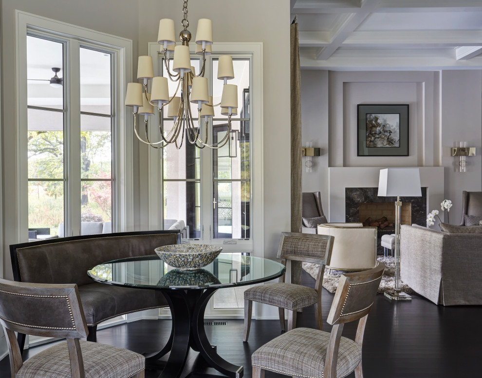 Пример оригинального дизайна: большая гостиная-столовая в стиле неоклассика (современная классика) с серыми стенами, темным паркетным полом, стандартным камином, коричневым полом, кессонным потолком и фасадом камина из камня