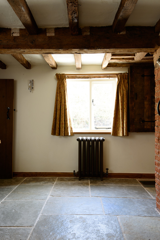 Immagine di una sala da pranzo rustica di medie dimensioni con pareti bianche, pavimento in pietra calcarea e cornice del camino in mattoni