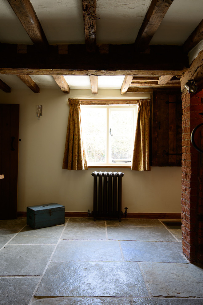 Esempio di una sala da pranzo stile rurale di medie dimensioni con pareti bianche, pavimento in pietra calcarea e cornice del camino in mattoni