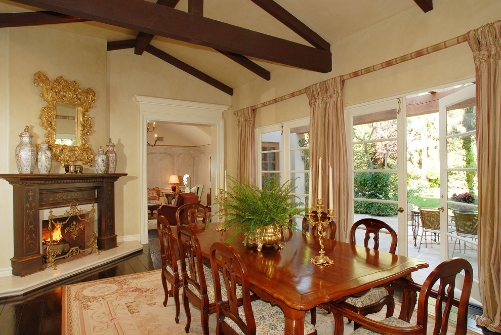 Classic dining room in Los Angeles with dark hardwood flooring and a standard fireplace.