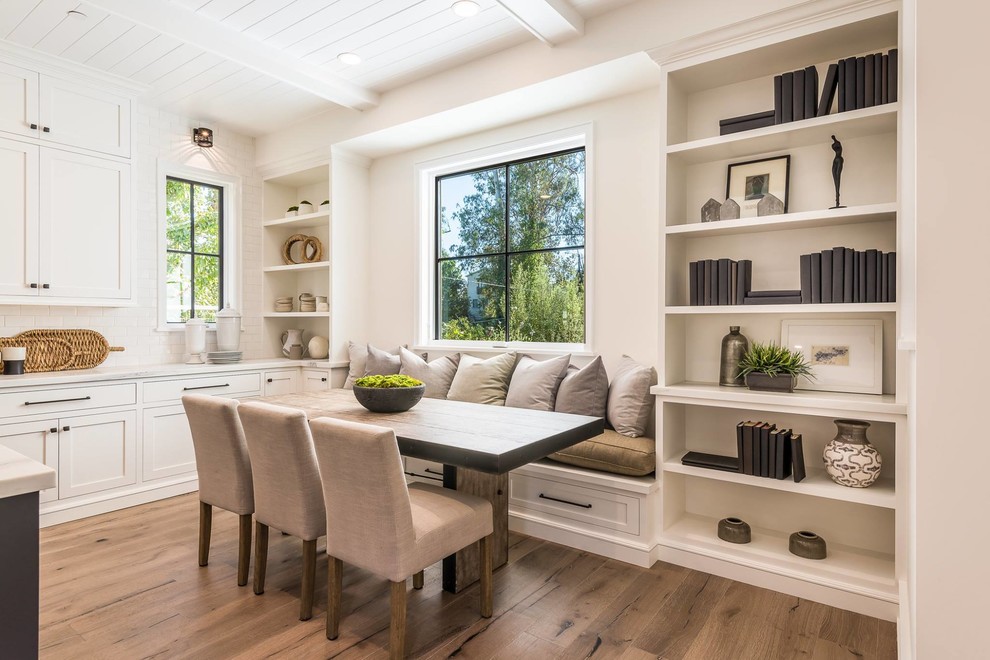 Example of a transitional medium tone wood floor and brown floor dining room design in Los Angeles with white walls