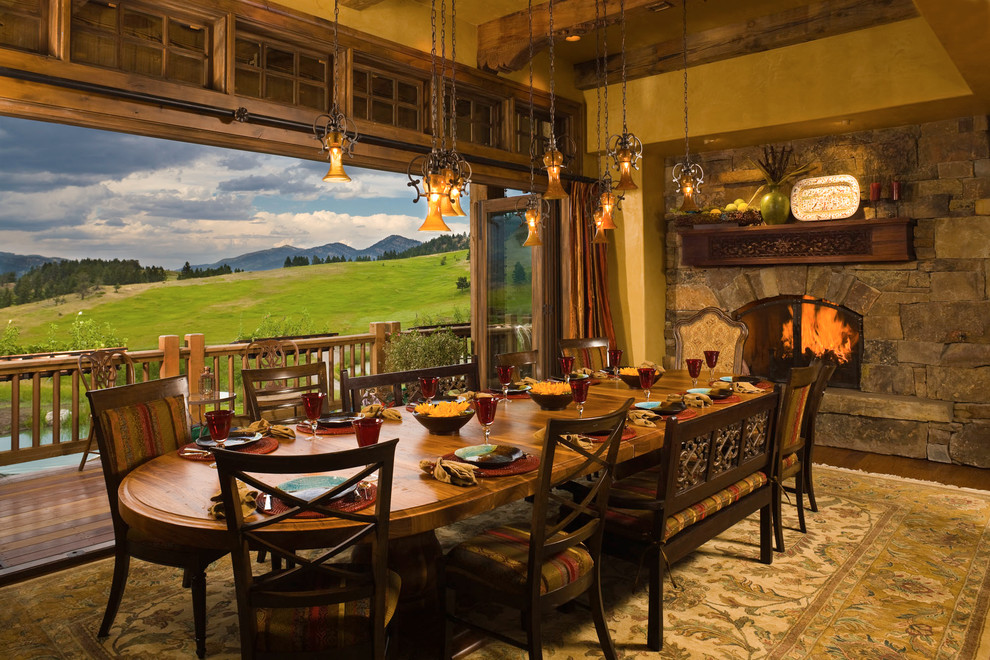 Aménagement d'une salle à manger montagne avec un manteau de cheminée en pierre et un mur jaune.