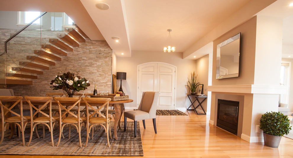 Idée de décoration pour une salle à manger design avec un mur beige, un sol en bois brun, une cheminée standard et éclairage.