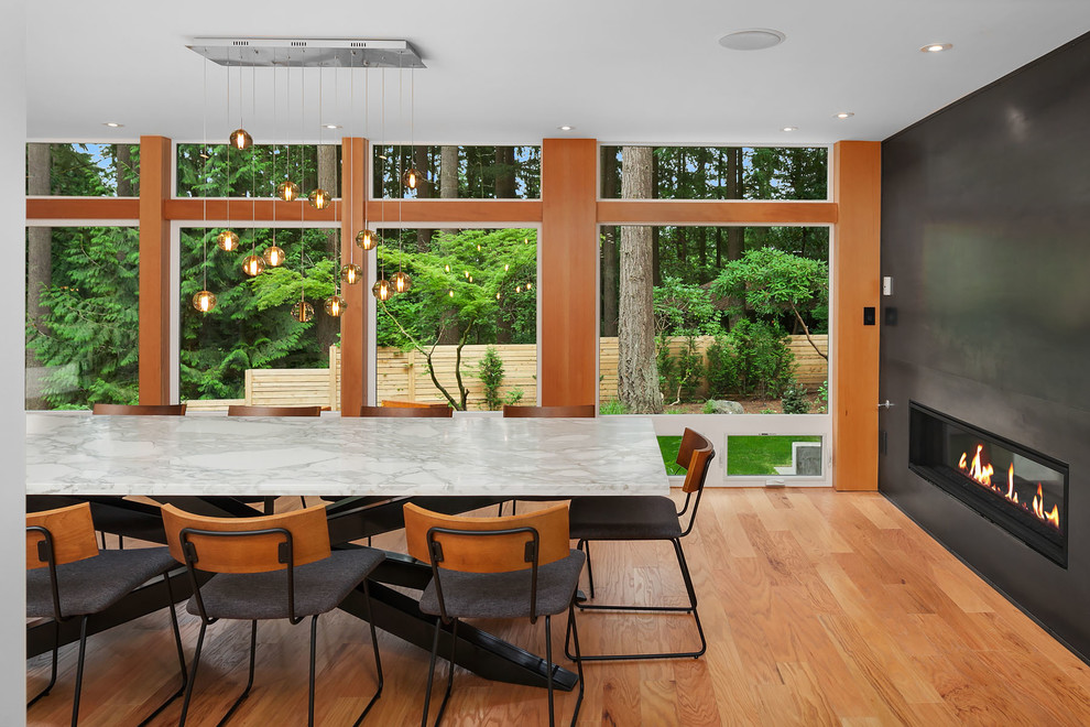 Modernes Esszimmer mit braunem Holzboden, schwarzer Wandfarbe, Gaskamin und grauem Boden in Seattle