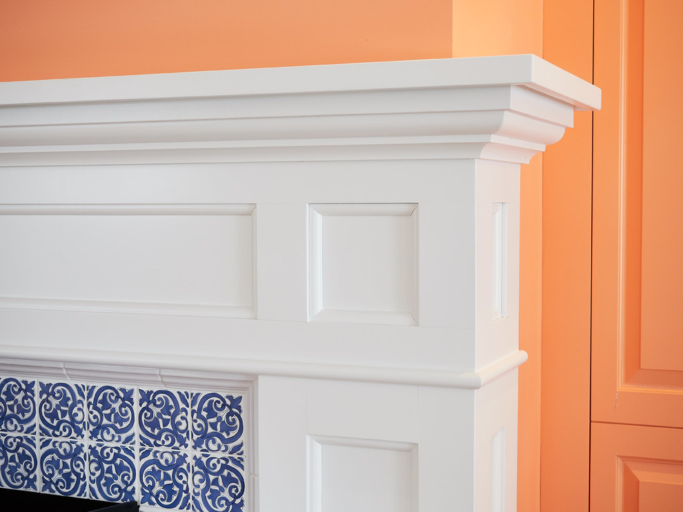 На фото: гостиная-столовая среднего размера в стиле неоклассика (современная классика) с оранжевыми стенами, паркетным полом среднего тона, стандартным камином, фасадом камина из плитки и коричневым полом с
