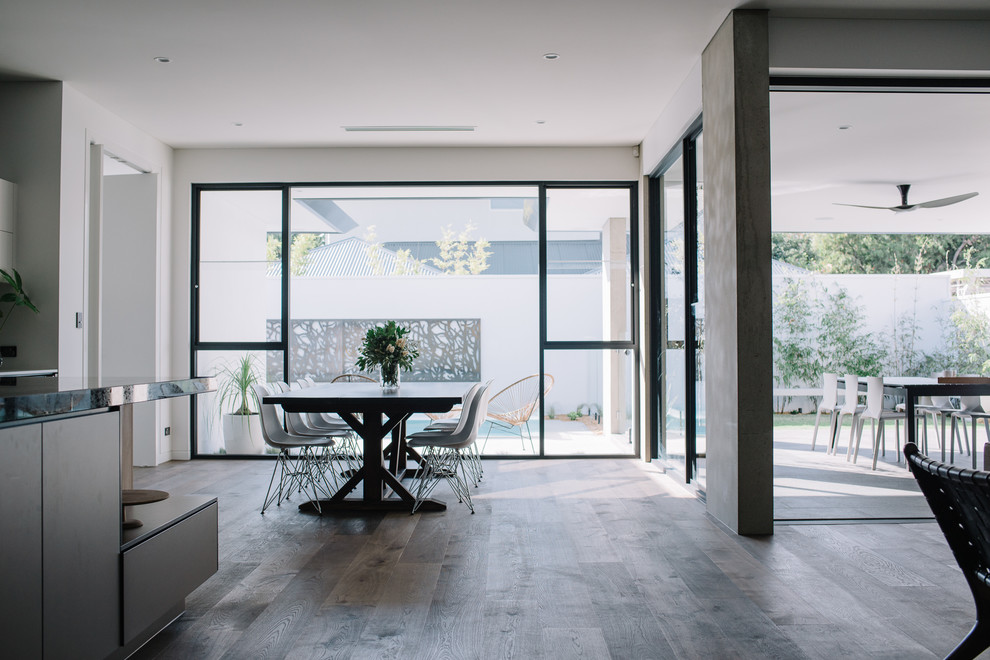 Modelo de comedor de cocina contemporáneo, grande, con paredes blancas y suelo de madera oscura
