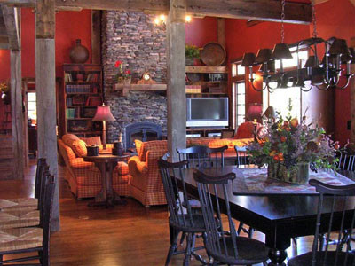 На фото: гостиная-столовая среднего размера в стиле рустика с оранжевыми стенами, темным паркетным полом, стандартным камином и фасадом камина из камня с