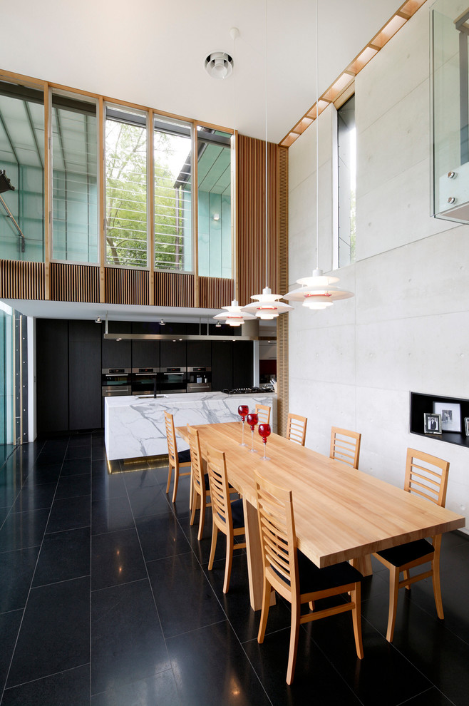 Cette image montre une grande salle à manger ouverte sur le salon design avec un sol noir.