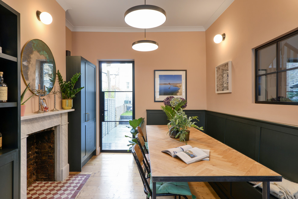 На фото: кухня-столовая в скандинавском стиле с розовыми стенами, стандартным камином и фасадом камина из камня с