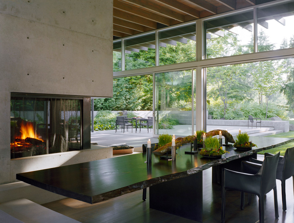 Cette photo montre une salle à manger moderne avec un manteau de cheminée en béton.
