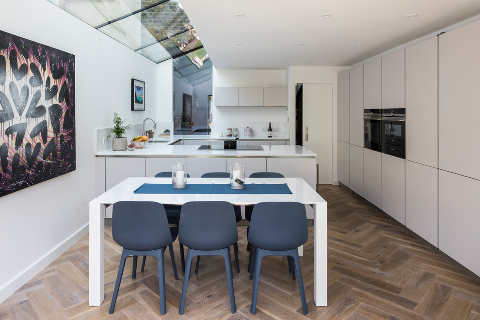 Пример оригинального дизайна: кухня-столовая в современном стиле с белыми стенами, паркетным полом среднего тона и коричневым полом