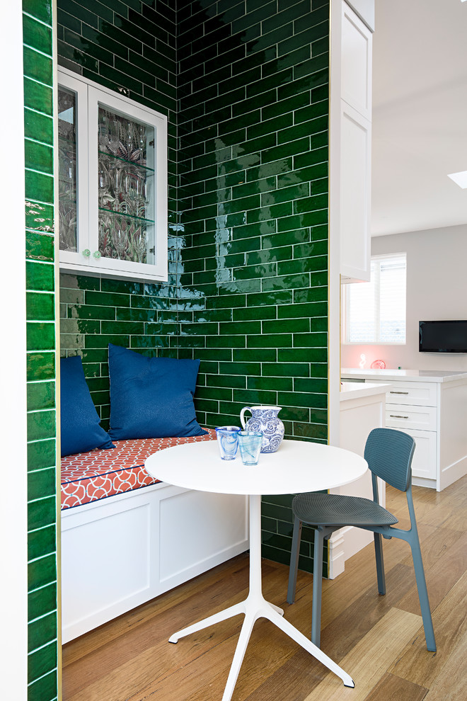 Cette image montre une salle à manger ouverte sur la cuisine bohème avec un mur vert, un sol en bois brun et un sol marron.