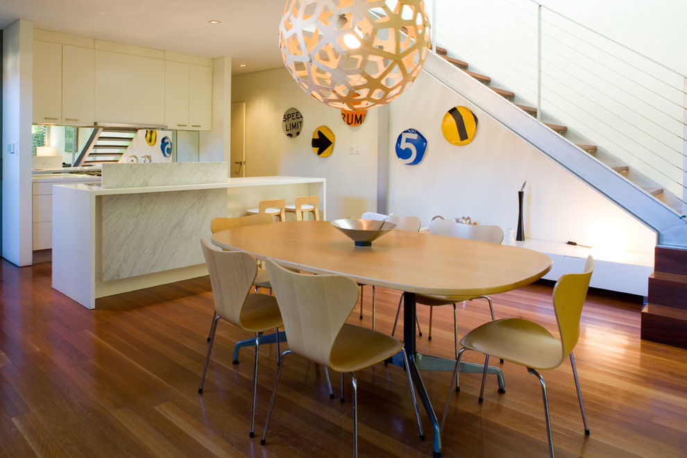 Ispirazione per una sala da pranzo aperta verso la cucina minimal di medie dimensioni con pareti bianche, pavimento in legno massello medio e nessun camino