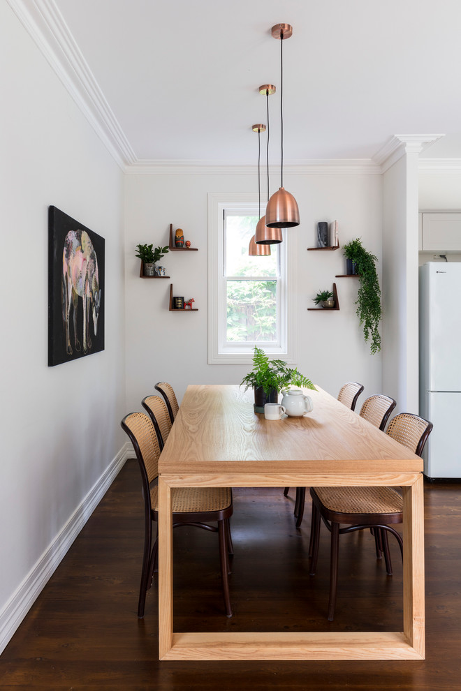 Cette image montre une salle à manger ouverte sur la cuisine traditionnelle de taille moyenne avec un mur blanc et un sol en bois brun.
