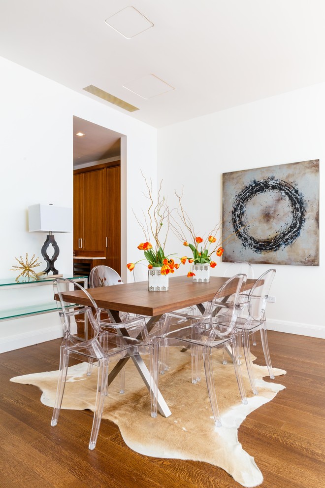 Aménagement d'une salle à manger contemporaine avec un mur blanc, un sol en bois brun et éclairage.