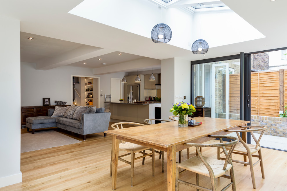 Photo of a contemporary open plan dining room in London with white walls and light hardwood flooring.