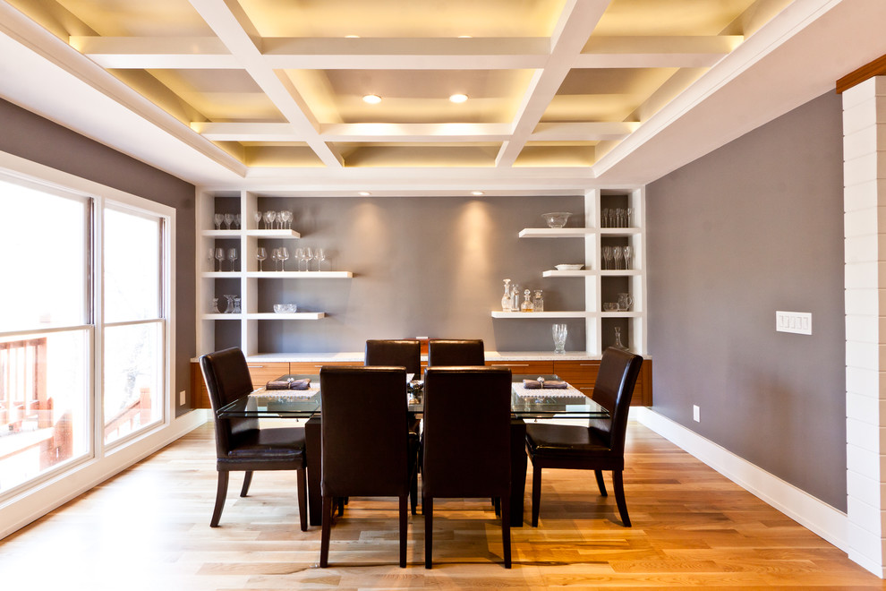 Immagine di una grande sala da pranzo design chiusa con pareti grigie, pavimento in legno massello medio, nessun camino e pavimento marrone