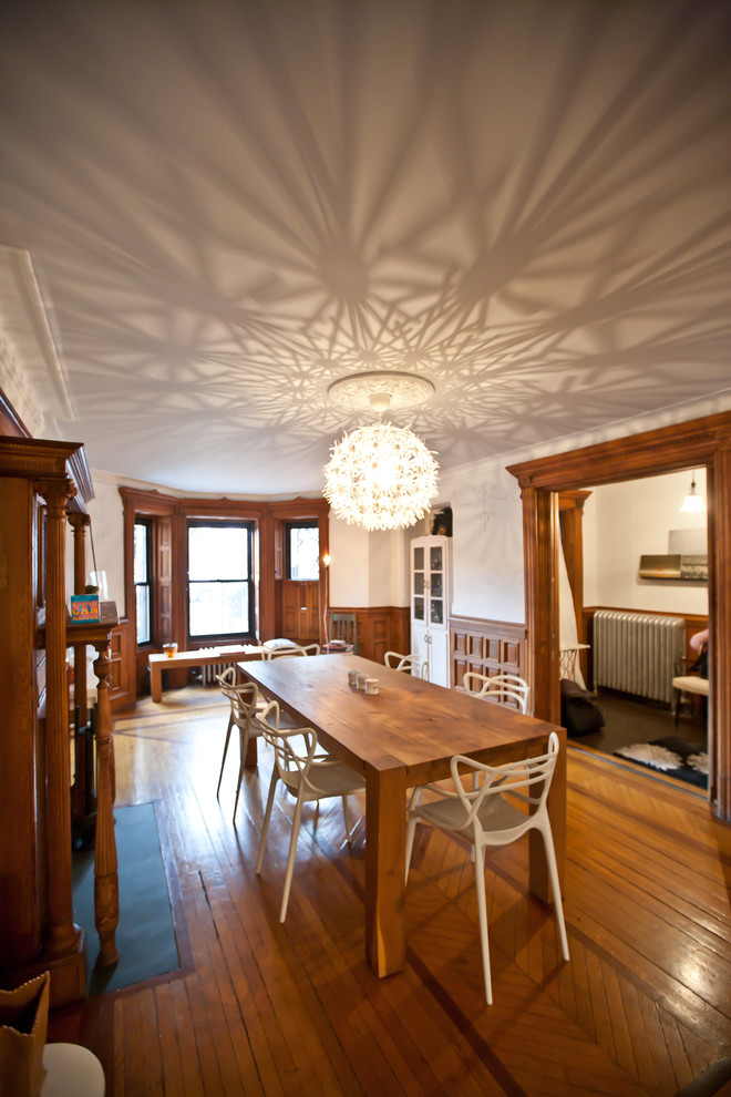 Imagen de comedor contemporáneo con paredes blancas y suelo de madera en tonos medios