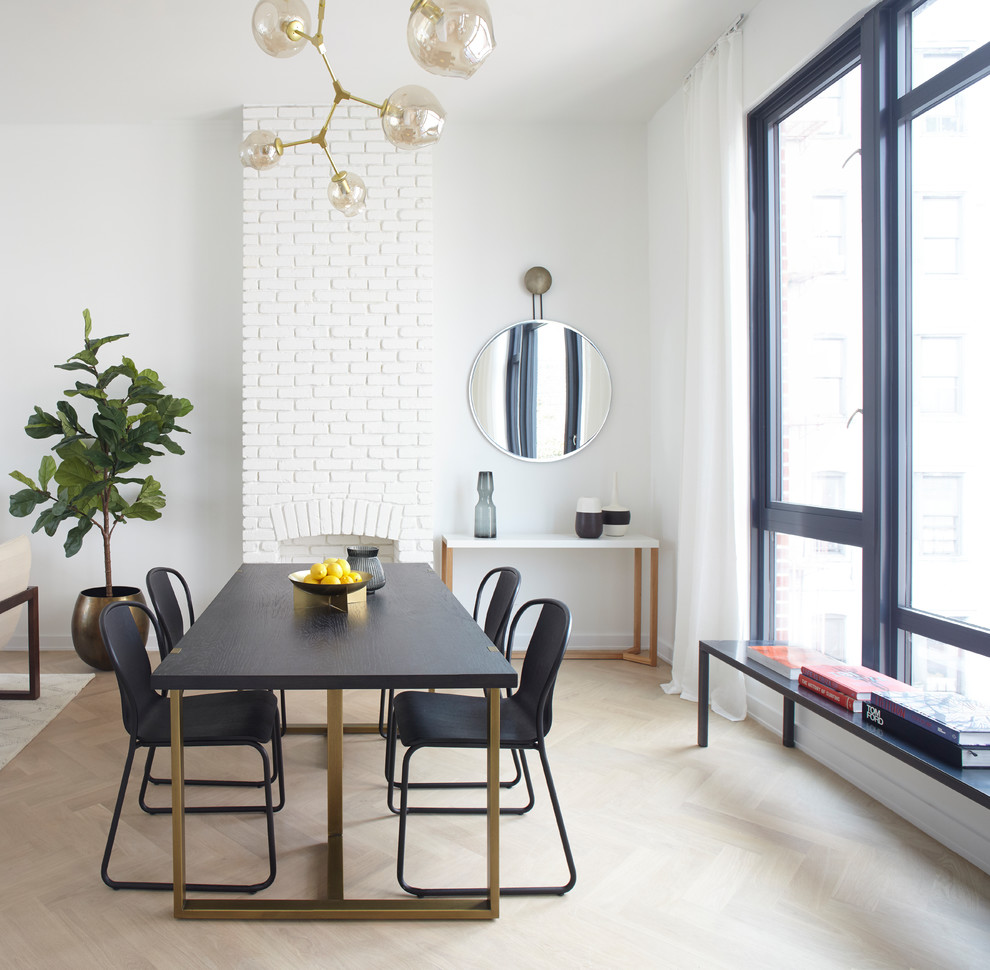 Cette image montre une salle à manger design avec un mur blanc, parquet clair, une cheminée standard, un manteau de cheminée en brique et un sol beige.