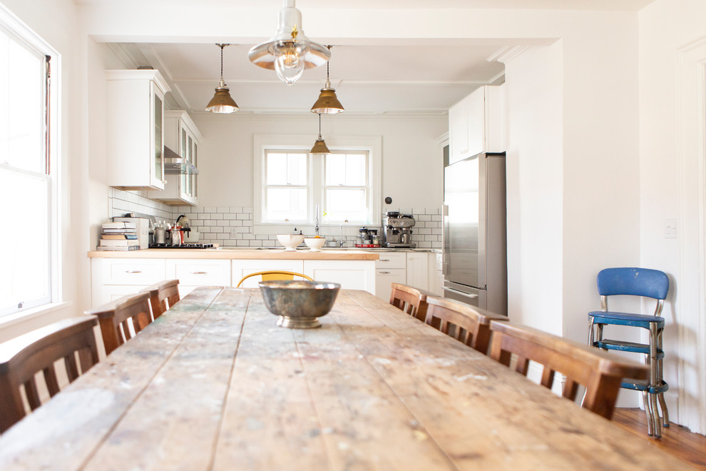 Cette image montre une salle à manger ouverte sur la cuisine rustique de taille moyenne avec un mur blanc.
