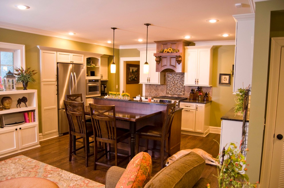 Inspiration pour une salle à manger ouverte sur le salon traditionnelle avec un mur vert et un sol en bois brun.