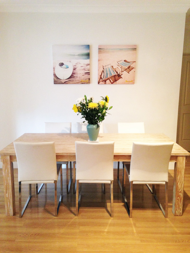 This is an example of a small coastal dining room in Sydney with white walls and light hardwood flooring.