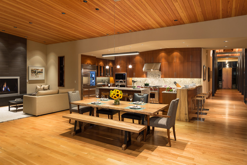 Aménagement d'une grande salle à manger ouverte sur la cuisine contemporaine avec un mur beige, un sol en bois brun, une cheminée standard, un manteau de cheminée en carrelage et un sol marron.