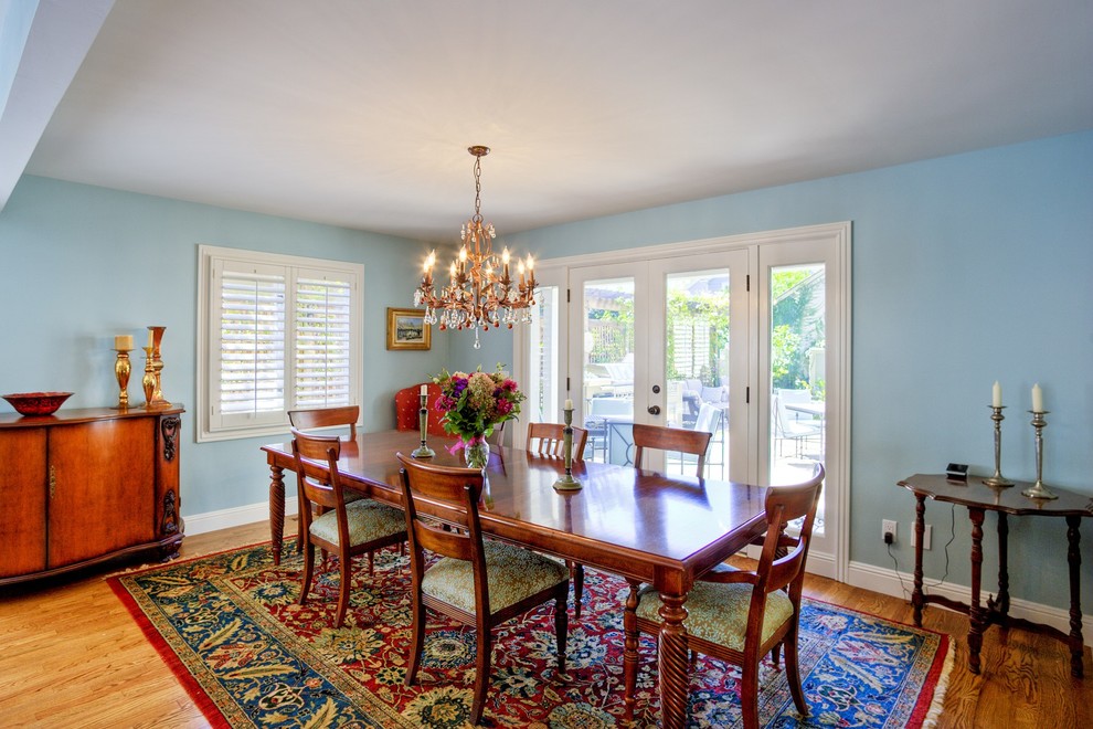 Exemple d'une salle à manger ouverte sur la cuisine chic de taille moyenne avec un mur bleu, parquet clair et aucune cheminée.
