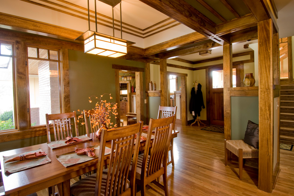 Réalisation d'une salle à manger craftsman fermée avec un mur vert et un sol en bois brun.