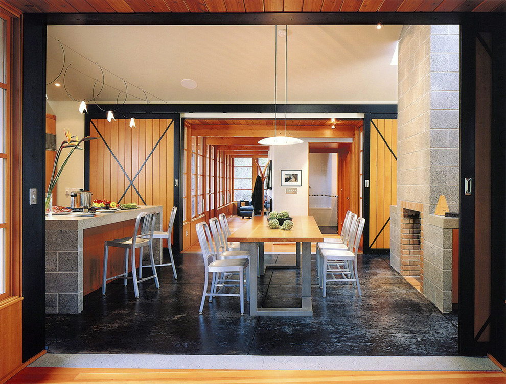 Uriges Esszimmer mit Kaminumrandung aus Beton und Betonboden in Seattle