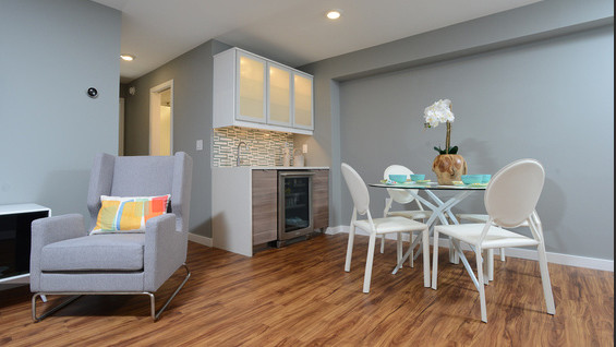 Kleine Moderne Wohnküche ohne Kamin mit grauer Wandfarbe, braunem Holzboden und braunem Boden in Sonstige