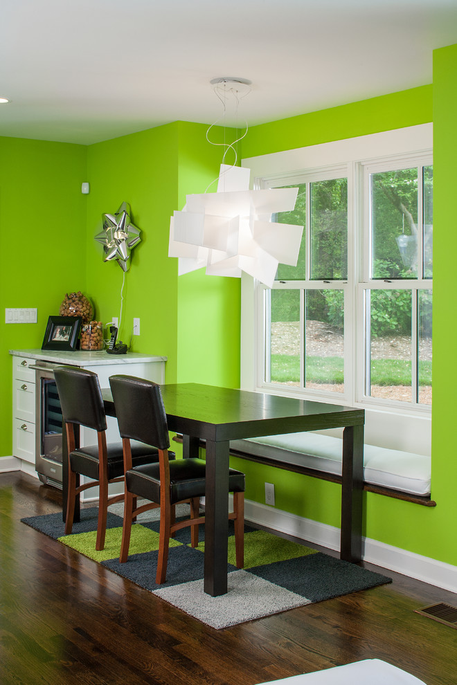 Cette photo montre une salle à manger tendance avec un mur vert et parquet foncé.