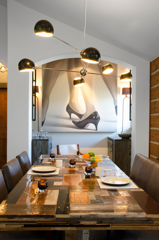 Cette image montre une petite salle à manger ouverte sur la cuisine design avec un mur blanc et éclairage.