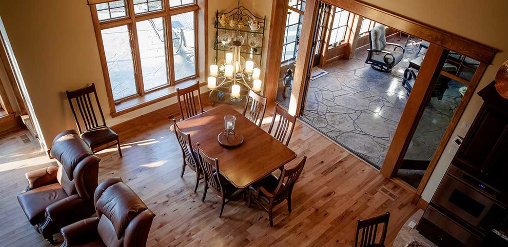 Cette image montre une salle à manger ouverte sur la cuisine chalet de taille moyenne avec un mur beige, un sol en bois brun, aucune cheminée et un sol marron.