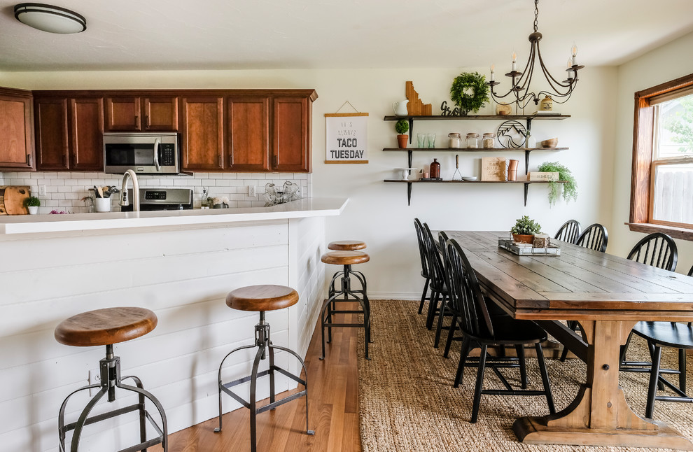 На фото: кухня-столовая среднего размера в стиле кантри с полом из ламината, коричневым полом и белыми стенами с