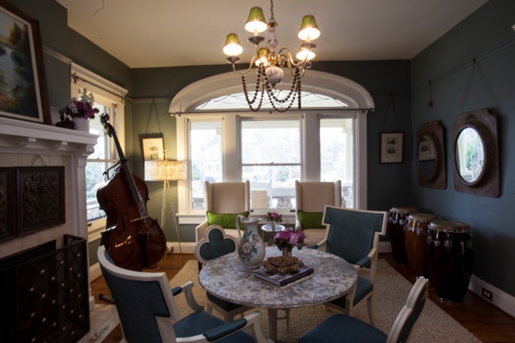 Aménagement d'une salle à manger ouverte sur le salon classique de taille moyenne avec un mur vert, un sol en bois brun, une cheminée standard et un manteau de cheminée en béton.