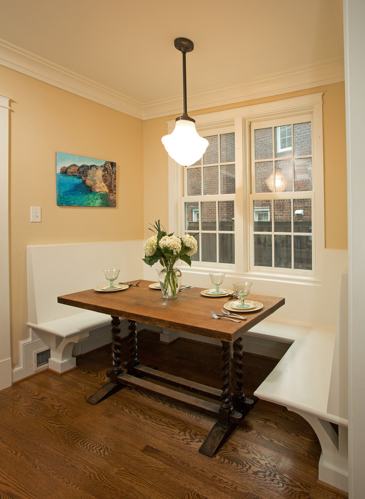 Aménagement d'une petite salle à manger ouverte sur la cuisine montagne avec un mur jaune et parquet foncé.