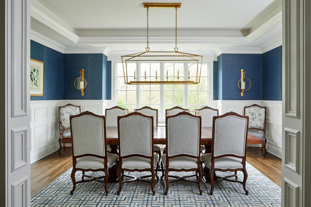 Example of a classic medium tone wood floor, brown floor, tray ceiling and wallpaper dining room design in Chicago with multicolored walls