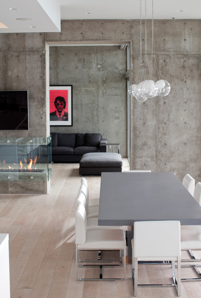 This is an example of an industrial dining room in Vancouver with a two-sided fireplace.