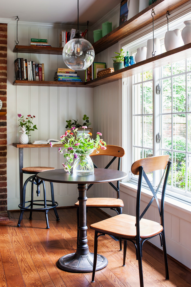 Kitchen/dining room combo - country medium tone wood floor and brown floor kitchen/dining room combo idea in Richmond with white walls, a standard fireplace and a brick fireplace